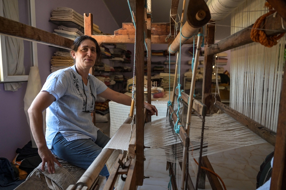Emel Duman, owner of Appollon Defne silk, poses as she weaves silk fabric in Antakya on July 10, 2023. Photo by Ozan KOSE / AFP