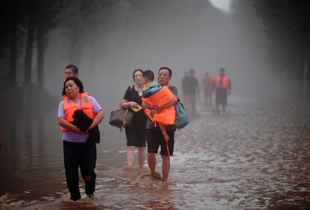 This photo taken on August 1, 2023 shows people evacuating from a flooded area after heavy rains in Zhuozhou, Baoding city, in China's northern Hebei province. Photos by CNS / AFP / China OUT