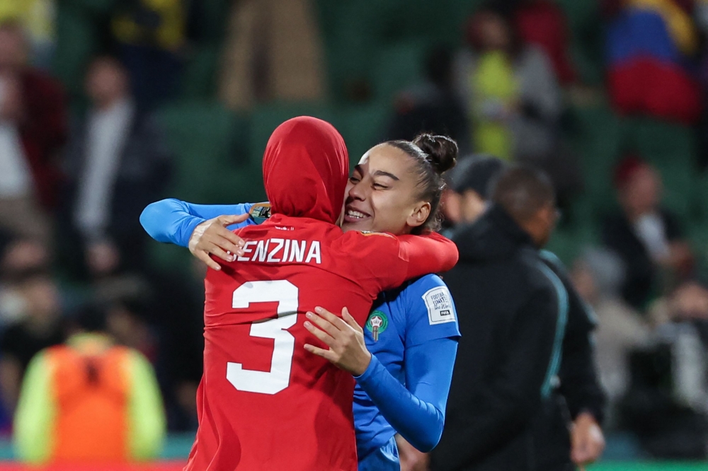 Morocco's defender #03 Nouhaila Benzina (L) embraces Morocco's goalkeeper #22 Ines Arouaissa as they celebrate their team's qualification to the knockout stage after the end of the Australia and New Zealand 2023 Women's World Cup Group H football match between Morocco and Colombia at Perth Rectangular Stadium in Perth on August 3, 2023. (Photo by Colin MURTY / AFP)