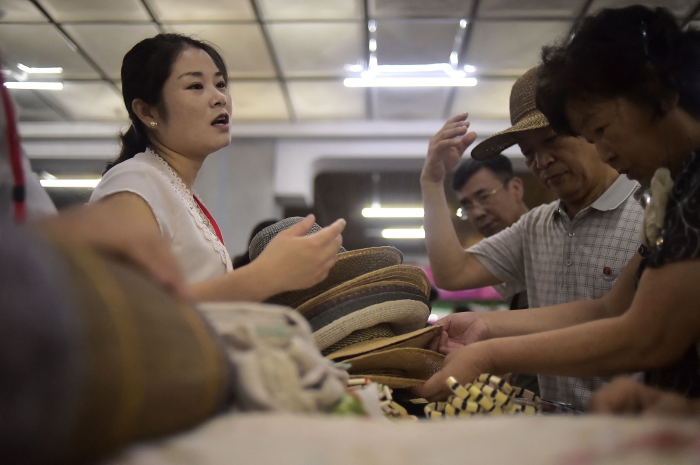 Visitors look at hats as they attend the opening of the 