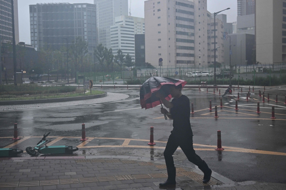 A man uses his umbrella in the southeastern port city of Busan on August 10, 2023, as Typhoon Khanun approaches. Photo by Anthony WALLACE / AFP