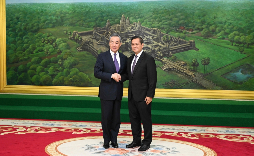 This handout photo taken and released by Cambodia's Government Cabinet on August 13, 2023 shows Cambodia's prime minister-designate Hun Manet (R) shaking hands with China's Foreign Minister Wang Yi at the Peace Palace in Phnom Penh. (Photo by Kok KY / CAMBODIA'S GOVERNMENT CABINET / AFP)
