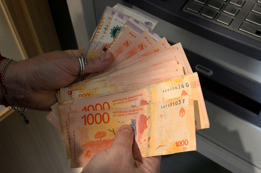 A woman withdraws Argentine pesos from an ATM machine at a bank in Buenos Aires on November 4, 2021. (Photo by Juan Mabromata / AFP)

