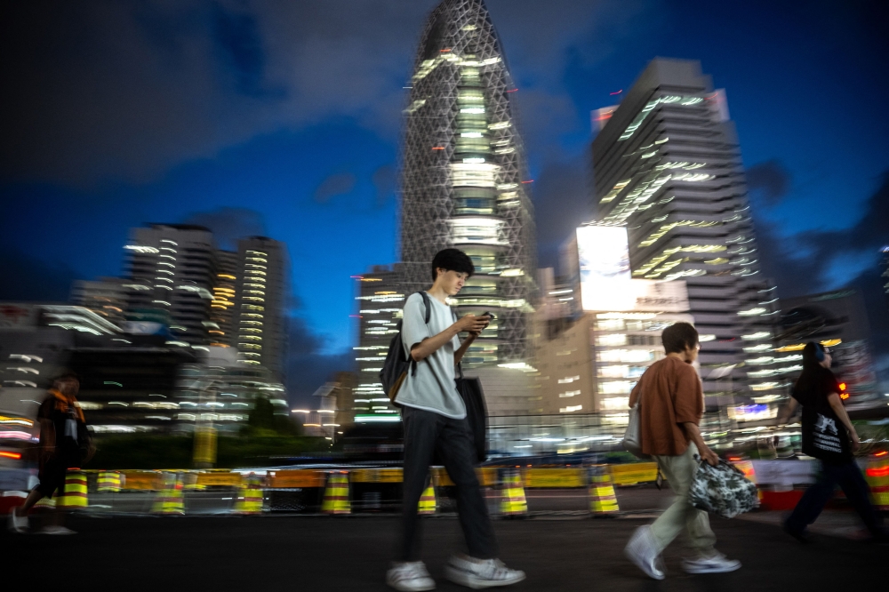 Pedestrians commute outside Shinjuku station during the evening hour of Tokyo on August 14, 2023. Photo by Philip FONG / AFP

