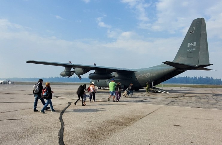 In this August 14, 2023, image released by Canada's Joint Task Force North, residents of Fort Smith, Northwest Territories, Canada, board a Royal Canadian Air Force aircraft as they are evacuated due to wildfires at Forth McMurray, Alberta. (Photo by Handout / Joint Task Force North / AFP)
