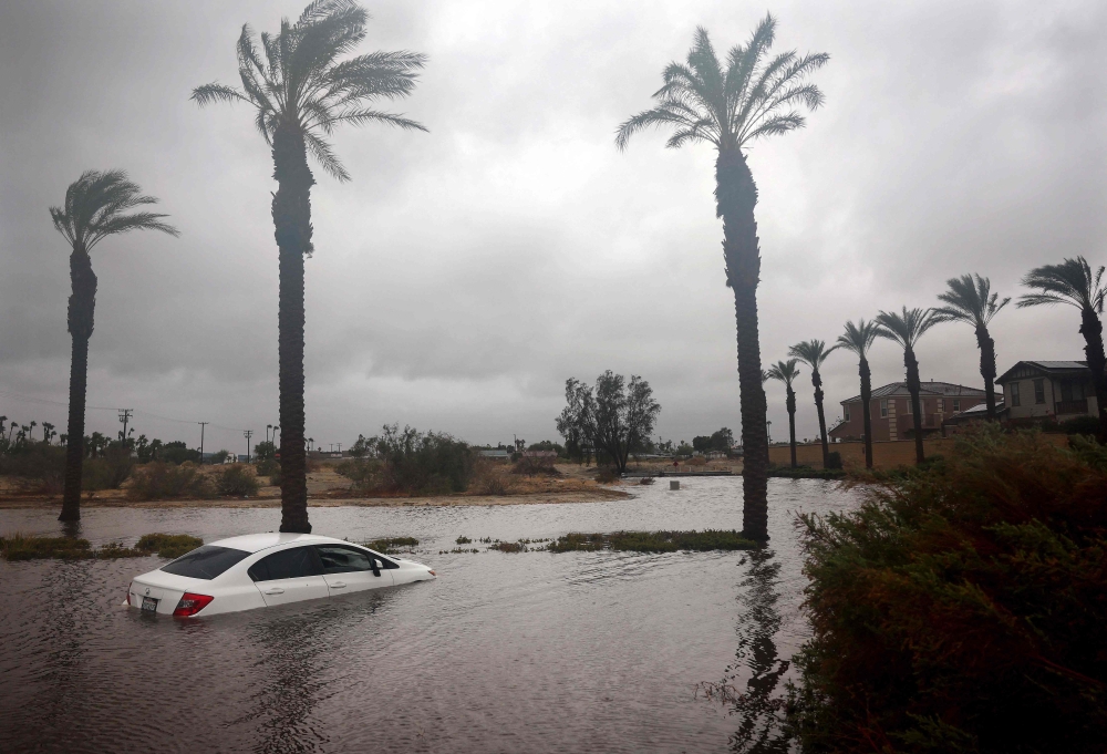 A car is partially submerged in floodwaters as Tropical Storm Hilary moves through the area on August 20, 2023 in Cathedral City, California. Photo by MARIO TAMA / GETTY IMAGES NORTH AMERICA / Getty Images via AFP