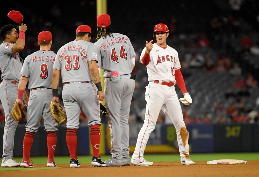 Designated hitter Shohei Ohtani #17 of the Los Angeles Angels is greeted by Cincinnati Reds infielders during a pitching change after Ohtani's double during the fifth of game two of a doubleheader at Angel Stadium of Anaheim on August 23, 2023 in Anaheim, California. Kevork Djansezian/Getty Images/AFP
