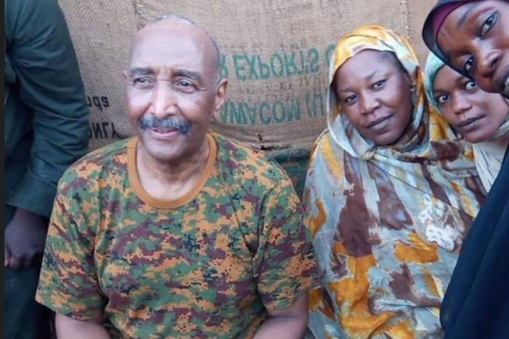 A handout image posted on the Sudanese Armed Forces's facebook page shows army chief General Abdel Fattah al-Burhan posing for a picture with civilians in Khartoum during a tour of a neighbourhood in the capital on August 24, 2023. (Photo by Sudanese Army / AFP)