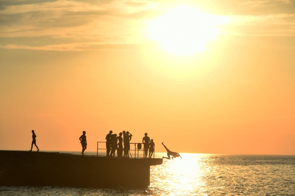 People dive into water at the Port Vieux beach in Biarritz, southwestern France, as the heatwave sweeps across France. (Photo by Gaizka Iroz / AFP)

