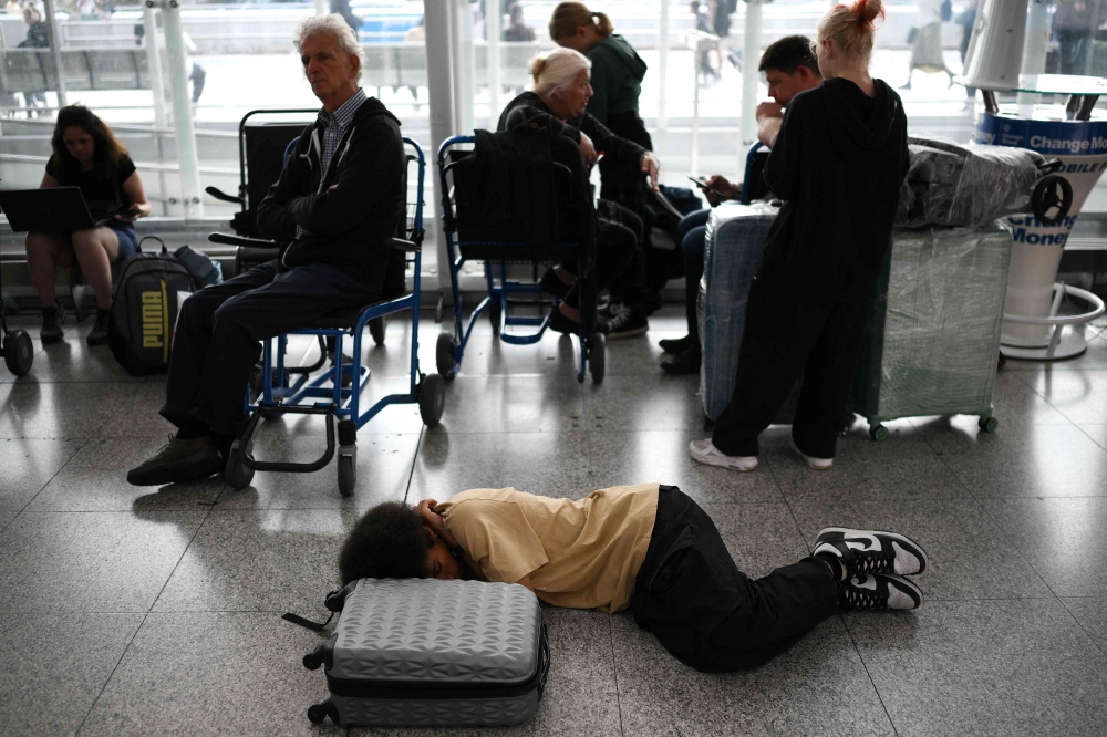 Passengers wait at Stansted Airport, north of London, on August 29, 2023 after UK flights were delayed over a technical issue. (Photo by Daniel Leal / AFP)