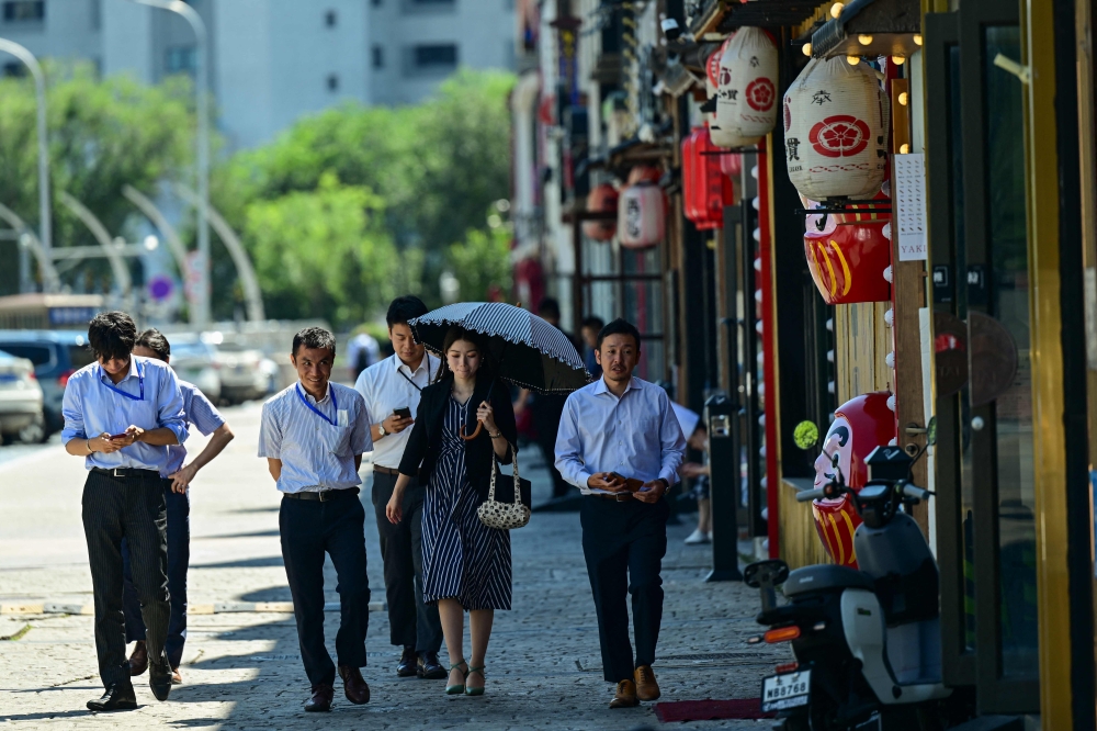 People walk past a Japanese restaurant near the Japanese embassy in Beijing on August 29, 2023.  (Photo by Pedro Pardo / AFP)

