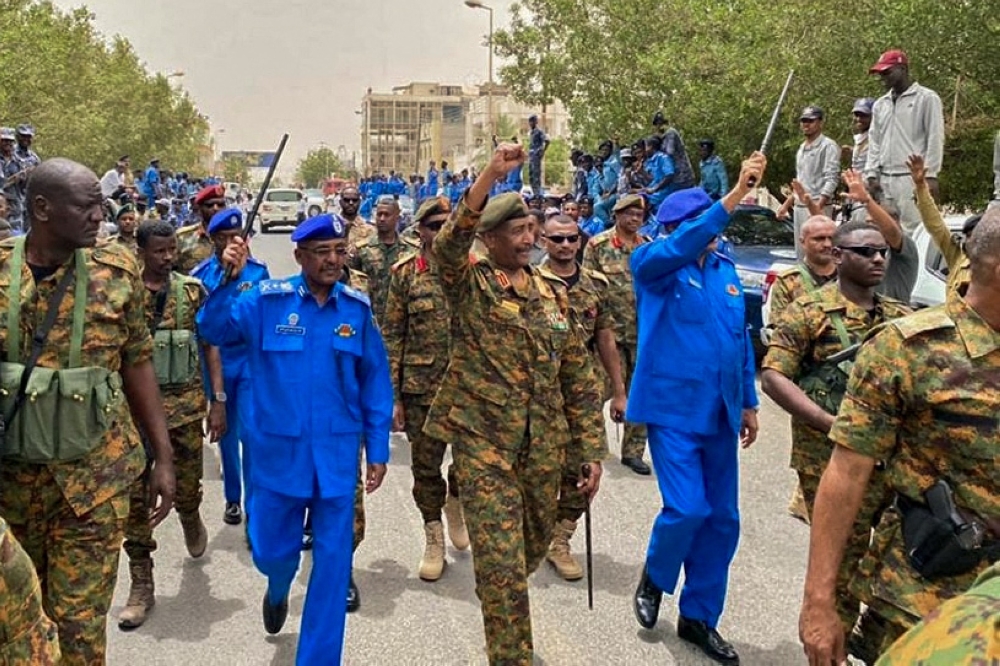 A handout image posted on the Sudanese Armed Forces's facebook page on August 31, 2023, shows army chief General Abdel Fattah al-Burhan (C) gesturing as he walks among other army members during a tour of a neighbourhood in Port Sudan, in the Red Sea state. (Photo by Sudanese Army / AFP)