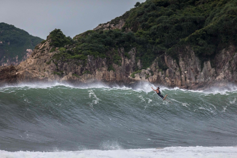 A surfer paddles over a wave generated by Typhoon Saola at a beach in Hong Kong on September 1, 2023.  (Photo by Dale De La Rey / AFP)