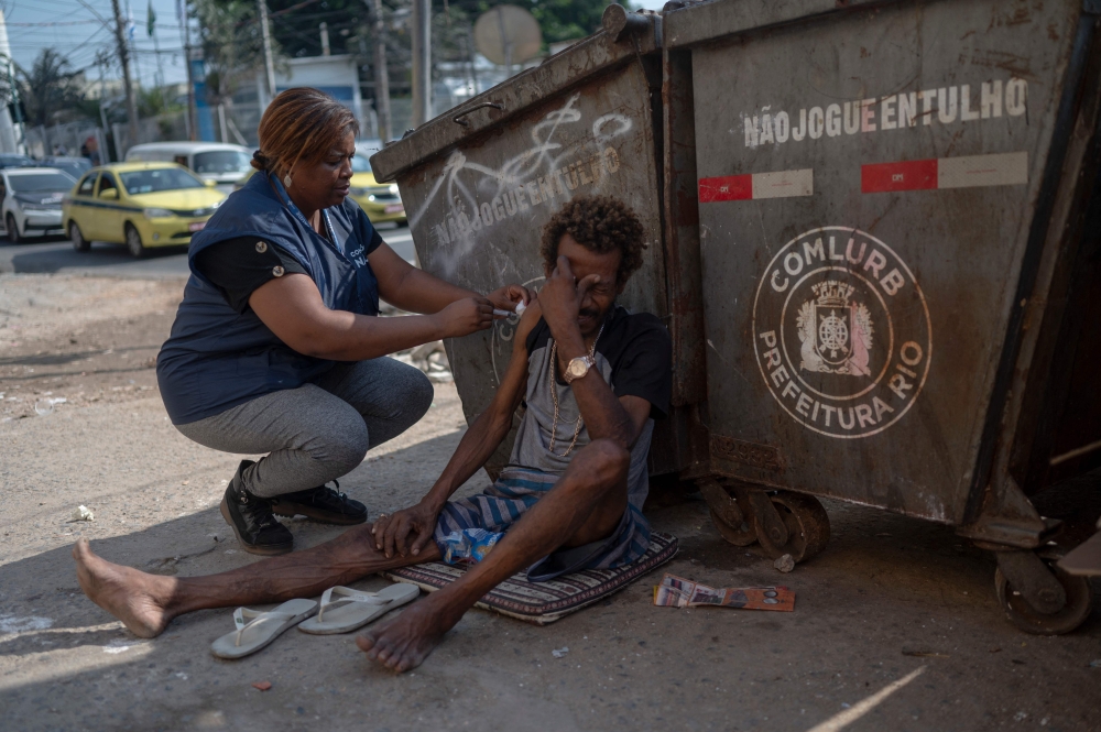 Nurse Assistant Sandra Maria (L) gives a COVID-19 vaccine to a homeless man in the suburbs of Rio de Janeiro, Brazil on July 12, 2023. (Photo by Mauro Pimentel /  AFP)
