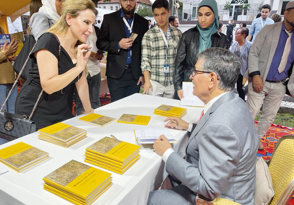 Minister of State and President of Qatar National Library, H E Dr. Hamad bin Abdulaziz Al Kawari signing copies of the German translation of his book Jusoor la Aswar.