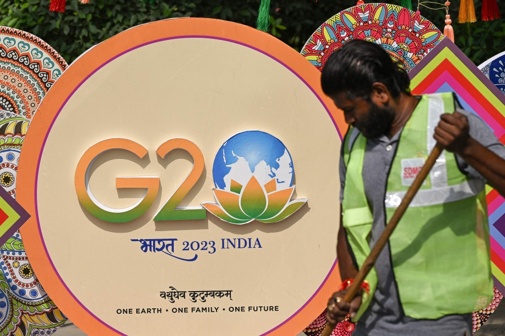 A municipal worker cleans a road near a G20 India summit logo ahead of its commencement in New Delhi on September 3, 2023. (Photo by Sajjad HUSSAIN / AFP)