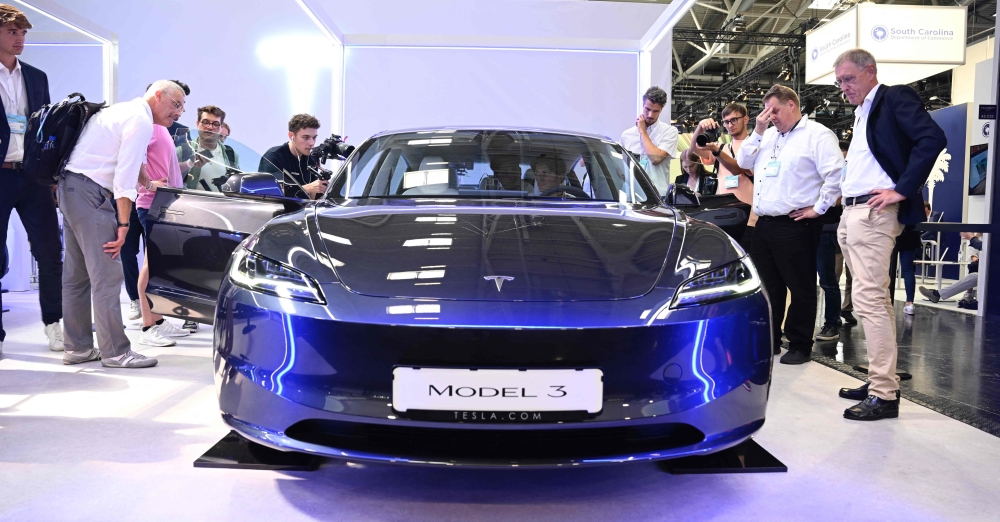 Visitors inspect a Tesla model 3 car on display at the International Motor Show (IAA) in Munich, southern Germany, on September 4, 2023. (Photo by Tobias Schwarz / AFP)