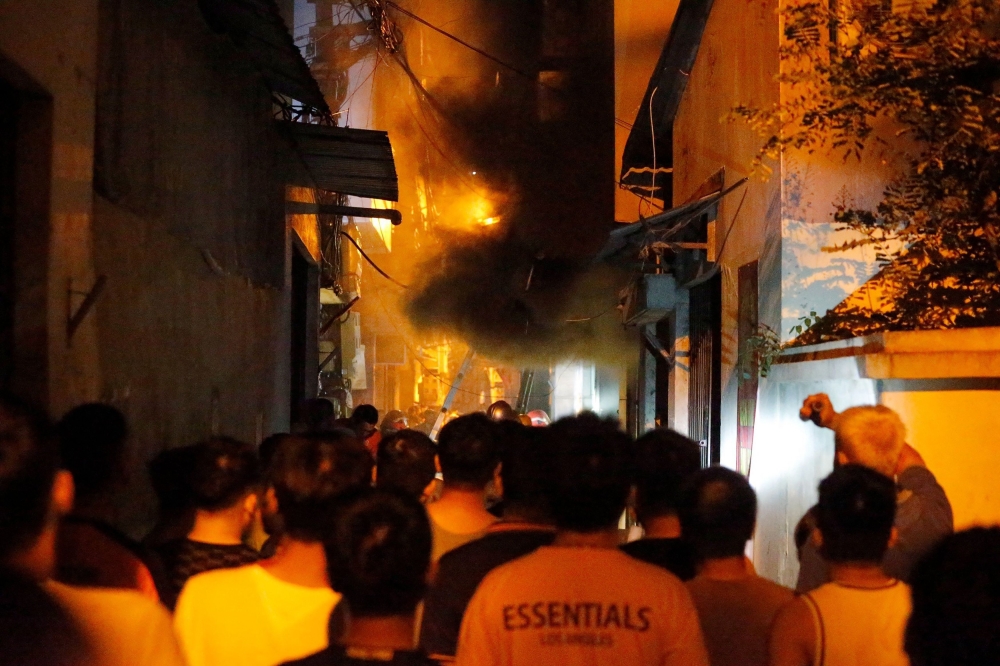People watch a fire at an apartment building in Hanoi on September 13, 2023. (Photo by AFP)