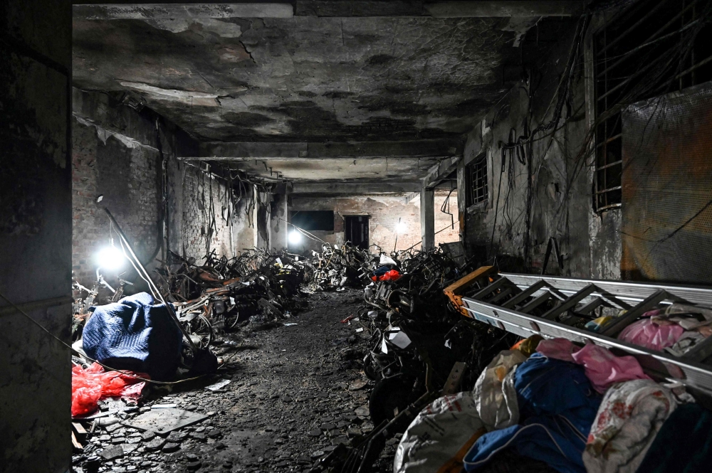This picture shows burned motorbikes and the damage on the ground floor of a 10-storey building after a major fire at an apartment block in Hanoi on September 13, 2023. Photo by Nhac NGUYEN / AFP