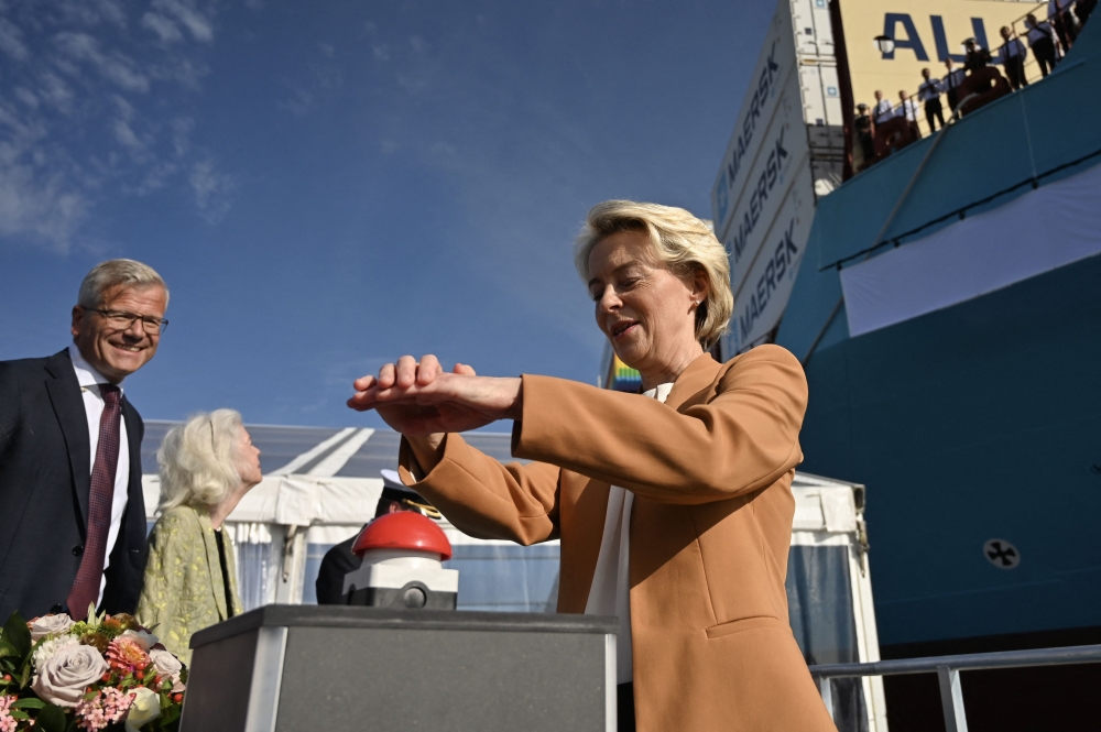 EU Commission President Ursula von der Leyen pushes the button under the eyes of the CEO of A.P. Moller-Maersk, Vincent Clerc (L) during a namegiving ceremony for the world's first methanol-enabled container vessel of A.P. Moller-Maersk in Copenhagen on September 14, 2023. (Photo by Sergei Gapon / AFP)