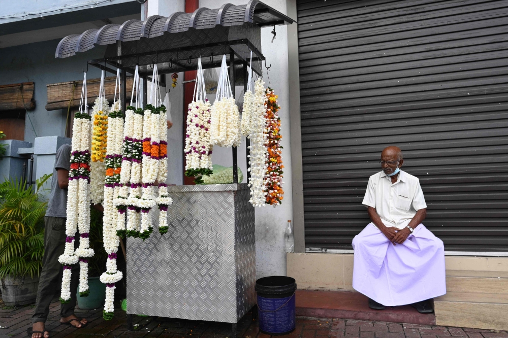 A man sits next to a flowers stall in Colombo on September 14, 2023. (Photo by Farooq Naeem / AFP)