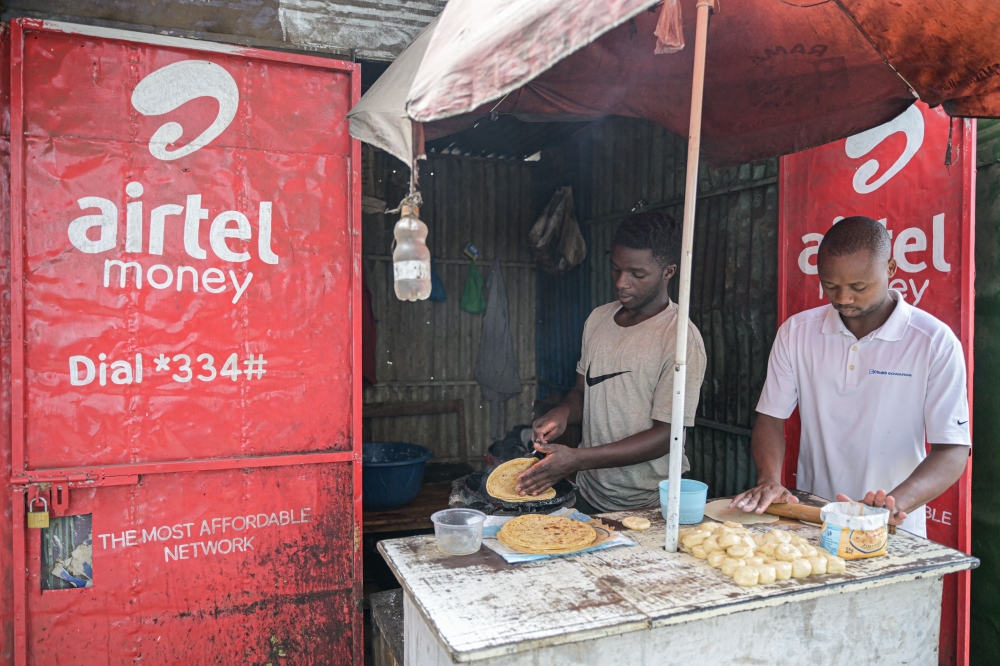 Food vendors prepare chapati inside a kiosk next to a sign advertising Airtel mobile money service, in Nairobi, on September 14, 2023. (Photo by Simon Maina / AFP)

