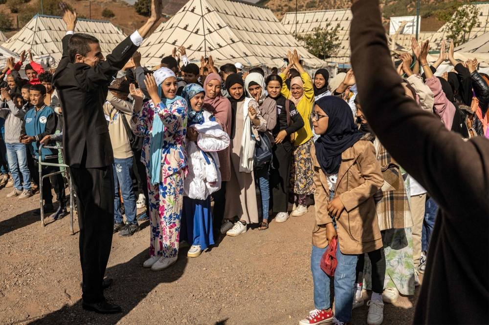 Students attend an assembly outside classroom tents at a make-shift school in the earthquake-hit village of Asni in al-Haouz province on September 18, 2023. (Photo by Fadel Senna / AFP)
