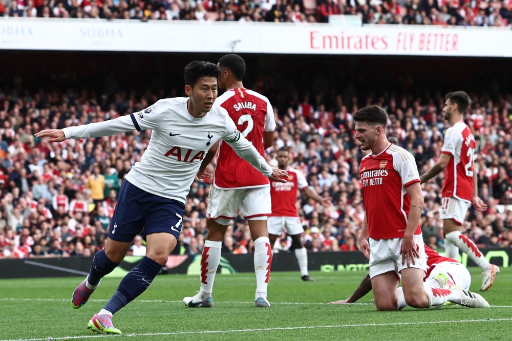 Tottenham Hotspur's South Korean striker #07 Son Heung-Min (L) celebrates after scoring their first goal during the English Premier League football match between Arsenal and Tottenham Hotspur at the Emirates Stadium in London on September 24, 2023. (Photo by HENRY NICHOLLS / AFP)
