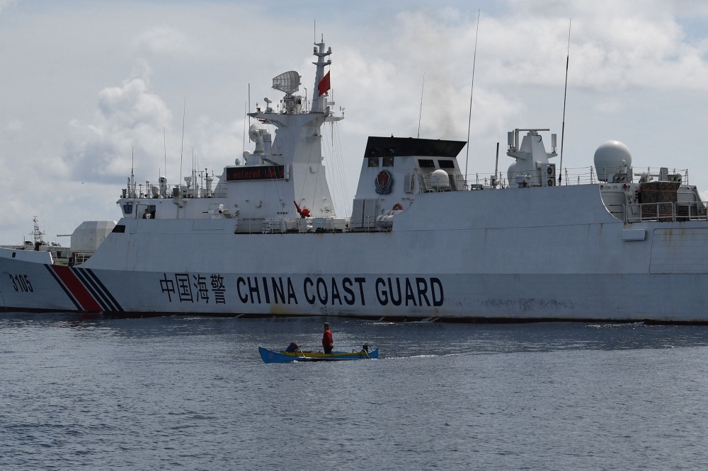 This photo taken on September 22, 2023 shows a wooden boat, with Philippine fisherman Arnel Satam on board, dwarfed by a Chinese coast guard vessel after he was intercepted for attempting to enter Scarborough Shoal in disputed waters of the South China Sea. (Photo by Ted Aljibe / AFP)