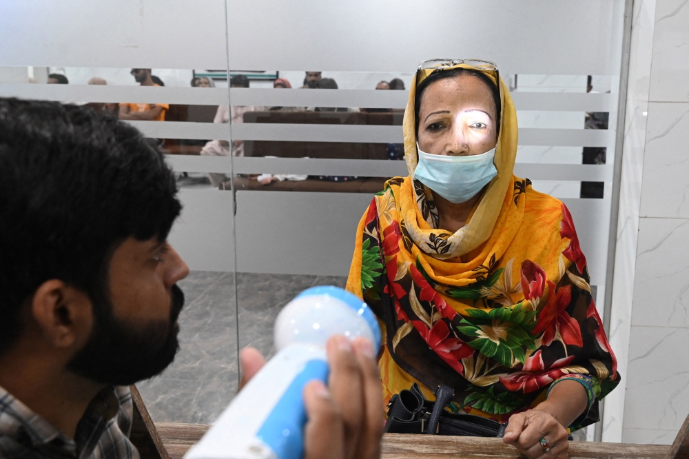 A doctor examines a patient suffering from an eye infection at a hospital in Lahore on September 27, 2023. (Photo by Arif Ali / AFP)