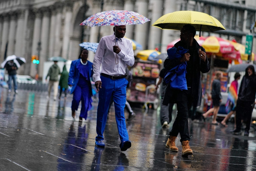 People walk under umbrellas during a coastal storm in Lower Manhattan on September 29, 2023 in New York City. (Photo by Eduardo Munoz Alvarez/Getty Images/AFP)
