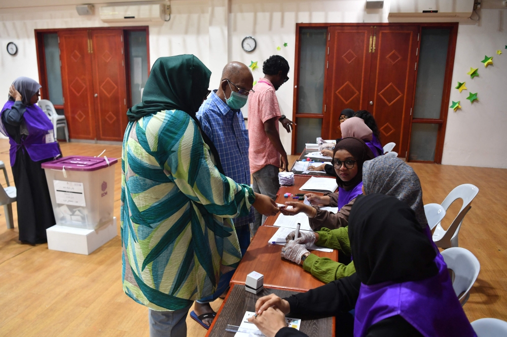 Election officials checks id cards of voters at a polling station during the second round of Maldives' presidential election in Male on September 30, 2023. (Photo by Mohamed Afrah / AFP)