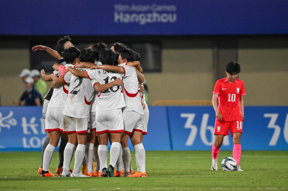 North Korea's players (L) celebrate after winning the women's football quarter-final match against South Korea during the Hangzhou 2022 Asian Games in Wenzhou, China's eastern Zhejiang province on September 30, 2023. (Photo by Hector RETAMAL / AFP)
