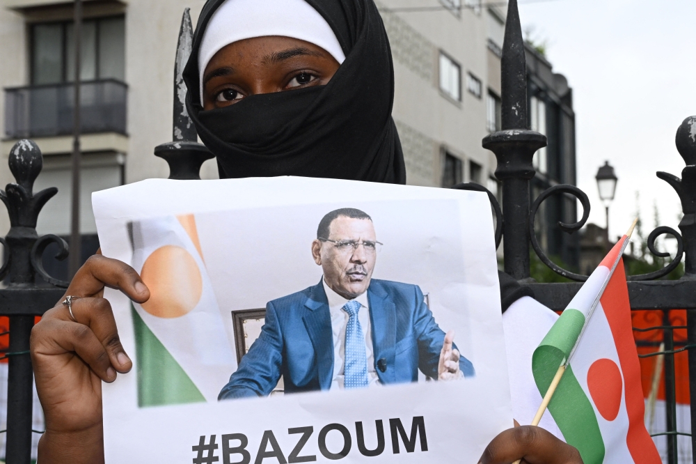File photo: A woman holds the image of ousted Niger President Mohamed Bazoum, 63, who has been held by coup plotters with his family in his official Niamey residence since July 26, during a protest outside the Niger Embassy, in Paris on August 5, 2023. (Photo by Stefano Rellandini / AFP)


