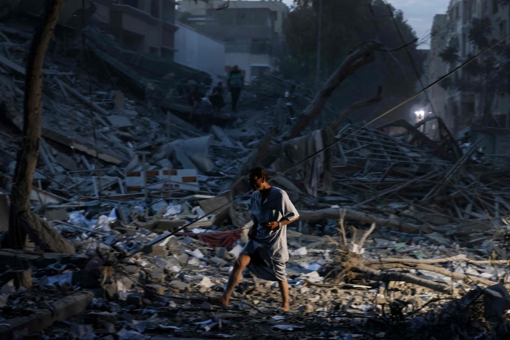 A man walks atop the rubble of a tower destroyed in an Israeli air stike in Gaza City on October 7, 2023. (Photo by MOHAMMED ABED / AFP)
