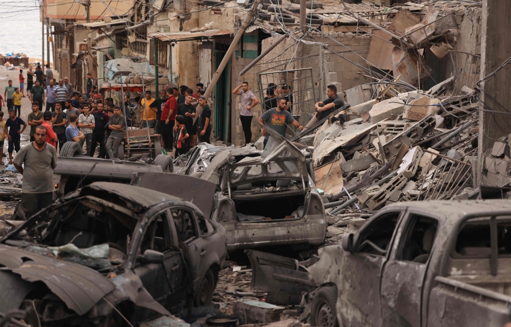 Palestinians inspect the destruction in a neighbourhood heavily damaged by Israeli airstrikes on Gaza City's Shati refugee camp early on October 9, 2023. (Photo by Mahmud Hams / AFP)
