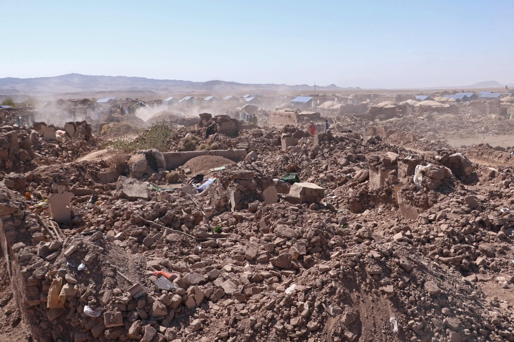 Afghan volunteers clear the debris of damaged village houses after a series of earthquakes in Zendeh Jan district of Herat province on October 9, 2023. (Photo by Mohsen Karimi / AFP)