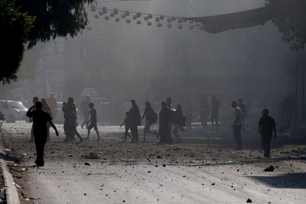 Palestinians evacuate a neighbourhood in Gaza City during Israeli airstrikes on October 11, 2023, as raging battles between Israel and the Hamas movement continued for the fifth consecutive day. Photo by MOHAMMED ABED / AFP