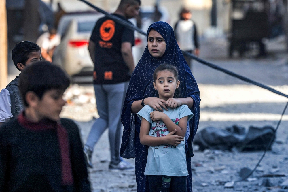 Youths look on during the search for the bodies of survivors and victims of a building collapse after Israeli bombardment in Rafah in the southern of Gaza Strip on October 19, 2023. (Photo by Mohammed Abed / AFP)