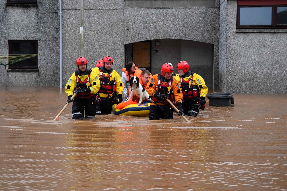 A couple and their dog are rescued by a Coastguard team from a flooded street in Brechin, northeast Scotland, on October 20, 2023 as Storm Babet batters the country. Photo by ANDY BUCHANAN / AFP