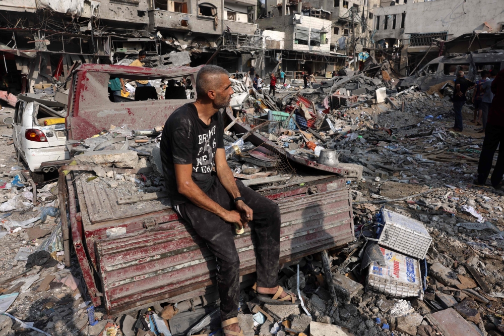 A man sits amid the destruction following Israeli strikes on Al-Shatee camp in Gaza City on October 28, 2023. (Photo by MOHAMMED ABED / AFP)