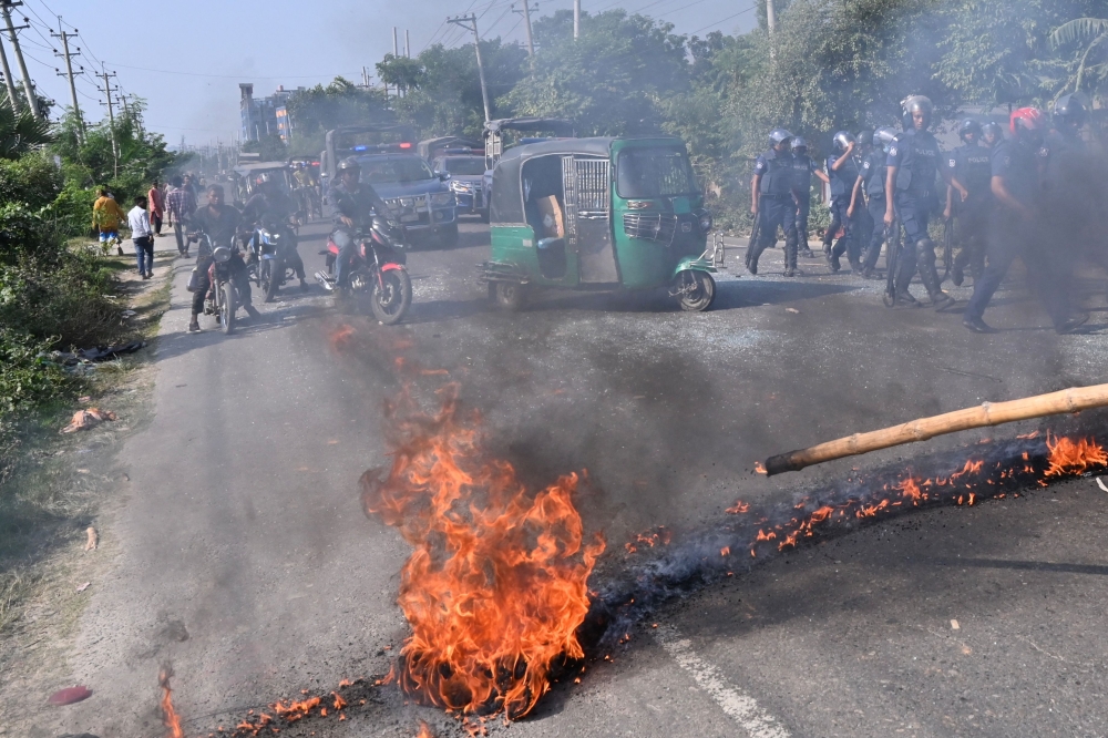 Motorists watch as Bangladesh Nationalist Party (BNP) activists set fire on a road as they attempt to block a highway during clashes with the police in Araihazar, some 40km from Dhaka, on October 31, 2023. (Photo by Munir Uz Zaman / AFP)
 