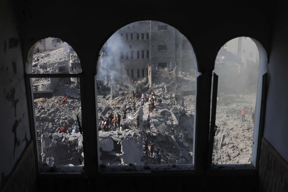 People sift through the smouldering rubble of buildings destroyed in an Israeli strike on the Bureij refugee camp in the central Gaza Strip on November 2, 2023. Photo by Mahmud HAMS / AFP