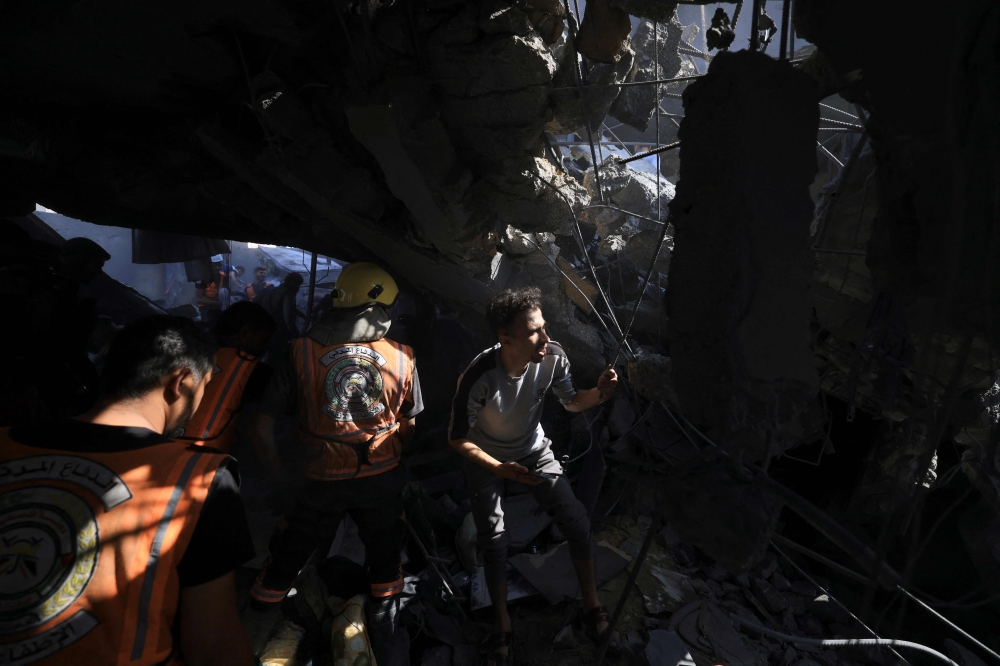 Palestinians look for survivors and victims following an Israeli air strike on a building in Khan Yunis in the southern Gaza Strip on November 3, 2023. Photo by Mahmud HAMS / AFP