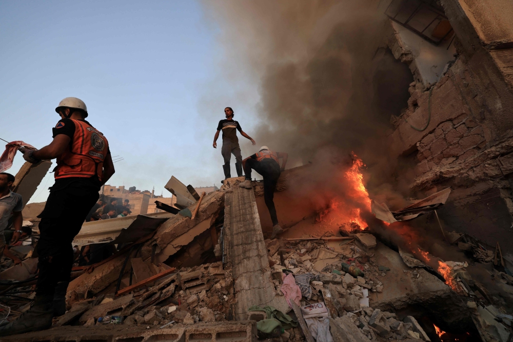 Palestinian rescuers attempt to put out a fire as they stand on the rubble of a collapsed building following a strike by the Israeli military on Khan Yunis in the southern Gaza Strip on November 4, 2023. (Photo by Mahmud Hams / AFP)