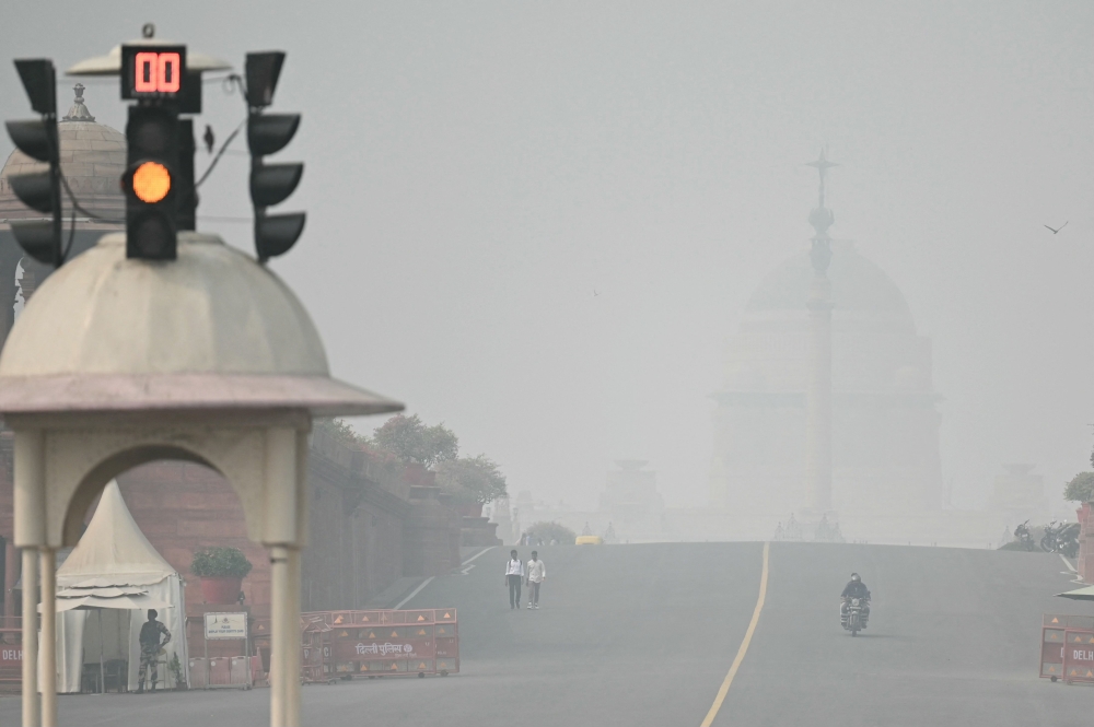 Commuters make their way near India's presidential palace Rashtrapati Bhavan amid heavy smoggy conditions in New Delhi on November 5, 2023. Photo by Arun SANKAR / AFP