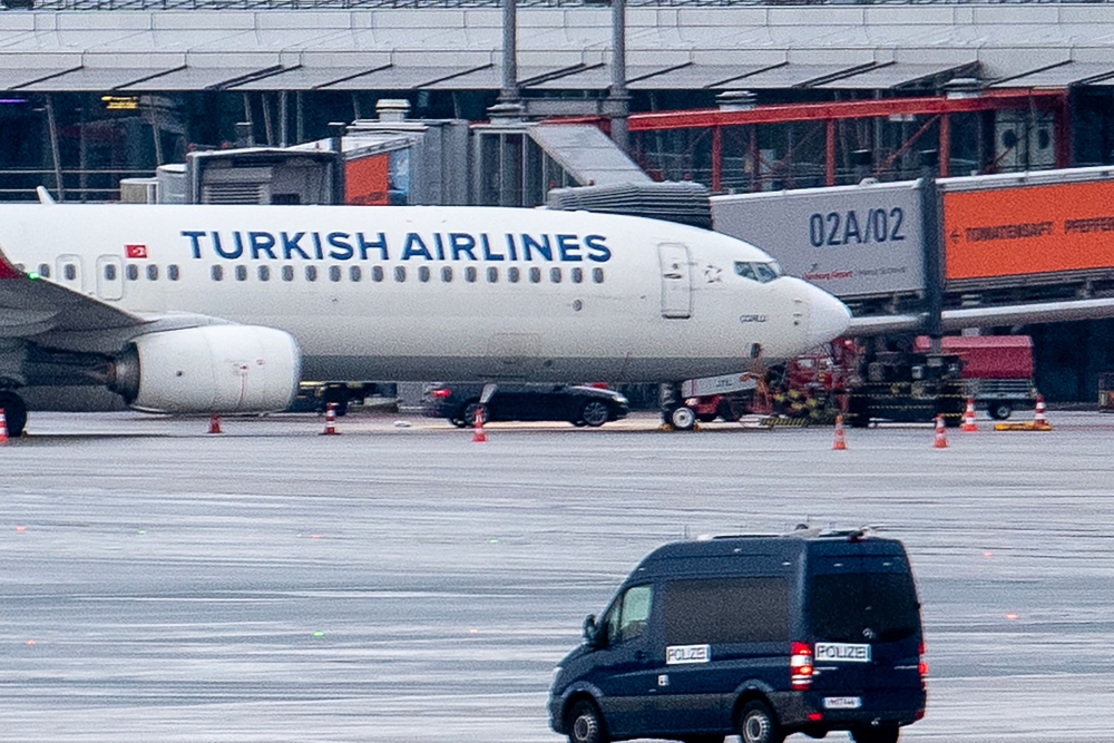 A police van observe the car of a hostage taker seen parked under a Turkish airline plane on the tarmac at the airport in Hamburg, northern Germany on November 5, 2023. Photo by NEWS5 / Schrِder / NEWS5 / AFP