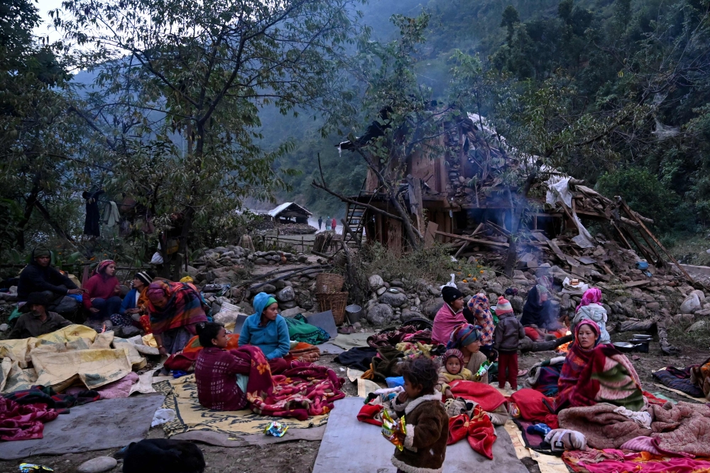 Survivors of a recent earthquake, rest under an open sky near a damaged house, in the early hours of Rukum district on November 5, 2023. Photo by Prakash MATHEMA / AFP