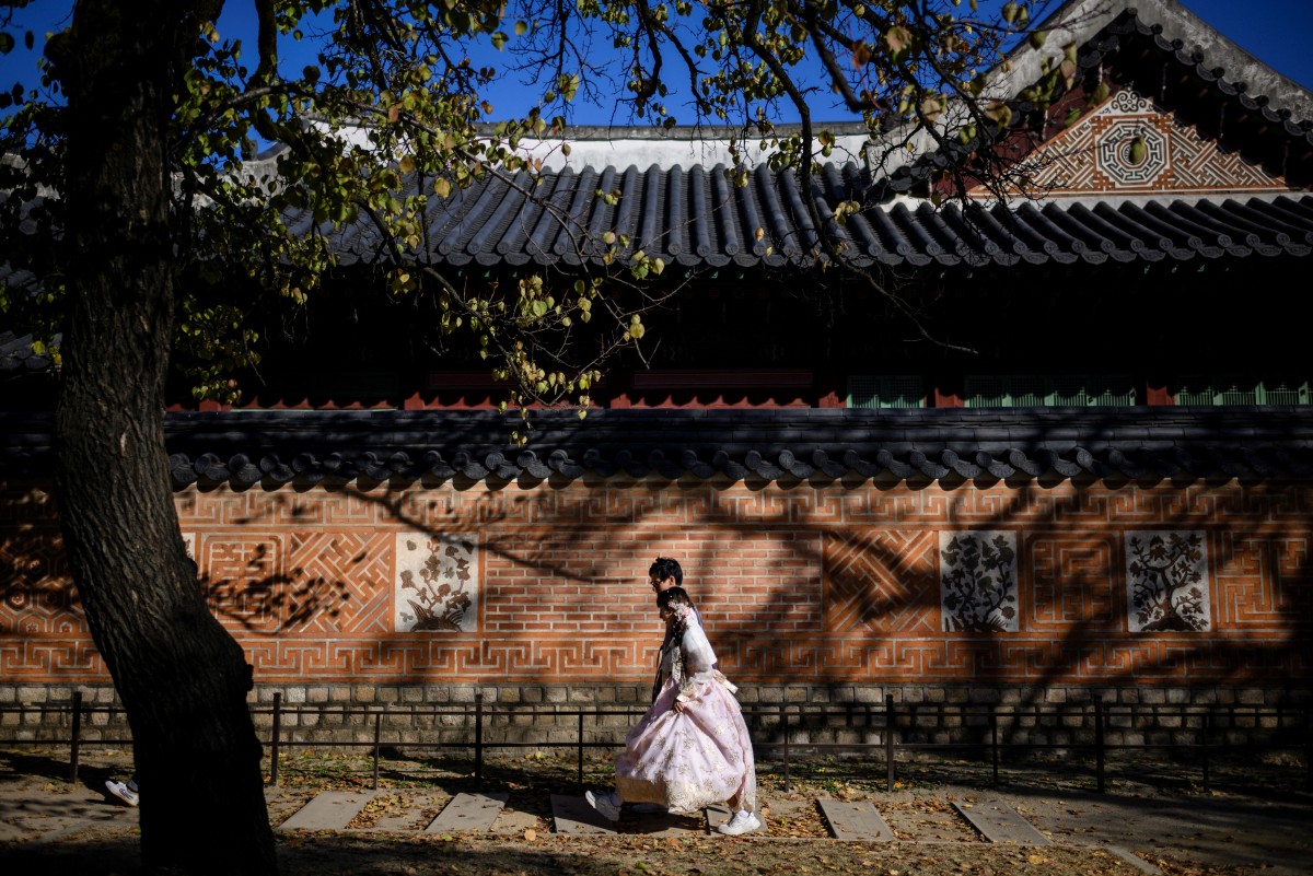 People wear traditional Hanbok dresses as they visit the Gyeongbokgung Palace grounds in Seoul on November 2, 2023. Photo by ANTHONY WALLACE / AFP
