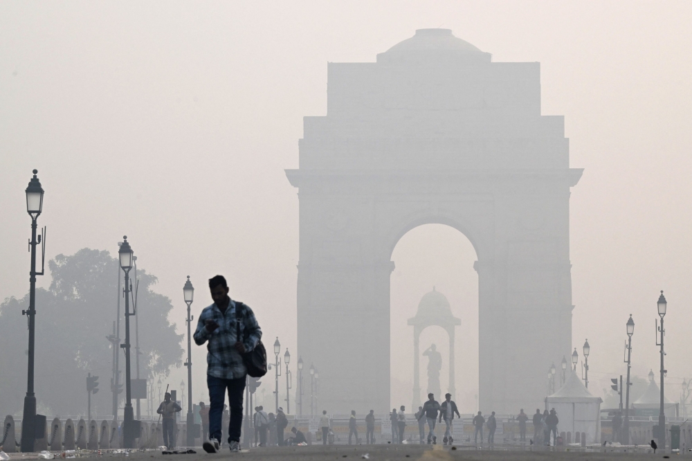 People walk along the Kartavya Path in front of the India Gate amid heavy smoggy conditions in New Delhi on November 13, 2023. Photo by Sajjad HUSSAIN / AFP